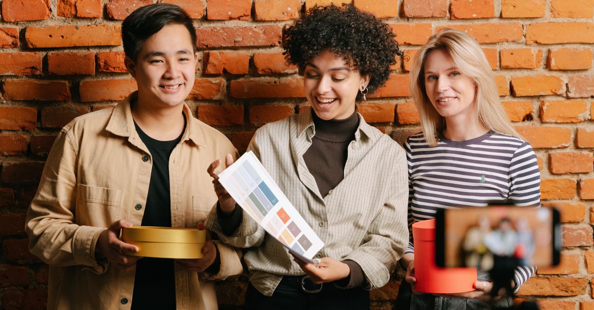 Three diverse people discussing packaging design with color samples, ideal for small business marketing.