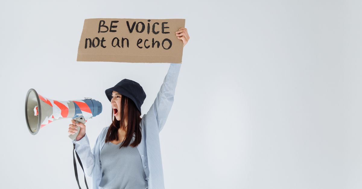 Empowered woman shouts message through megaphone, holding sign that reads 'Be voice, not an echo'.