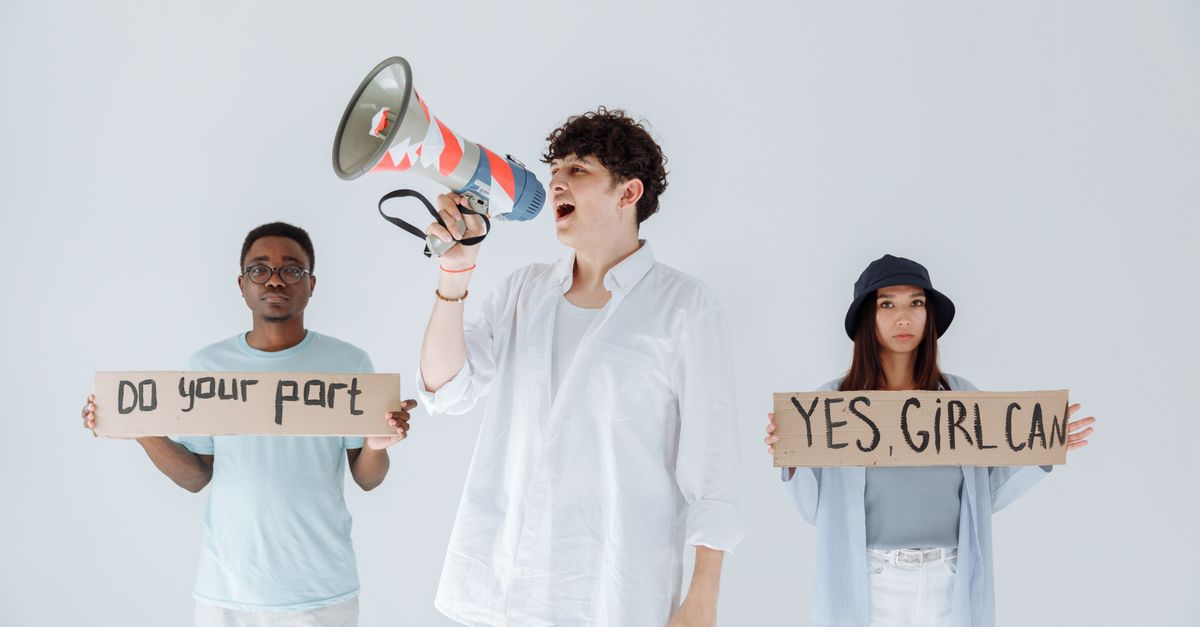 A diverse group of young adults protesting with signs and a megaphone, promoting activism and social change.