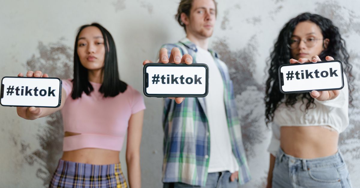 Group of young adults holding phones with #tiktok indoors, showcasing social media culture.