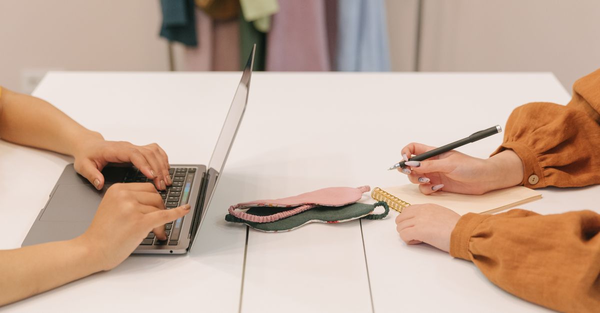 Two people working at a modern desk with a laptop and notebooks, reflecting teamwork.