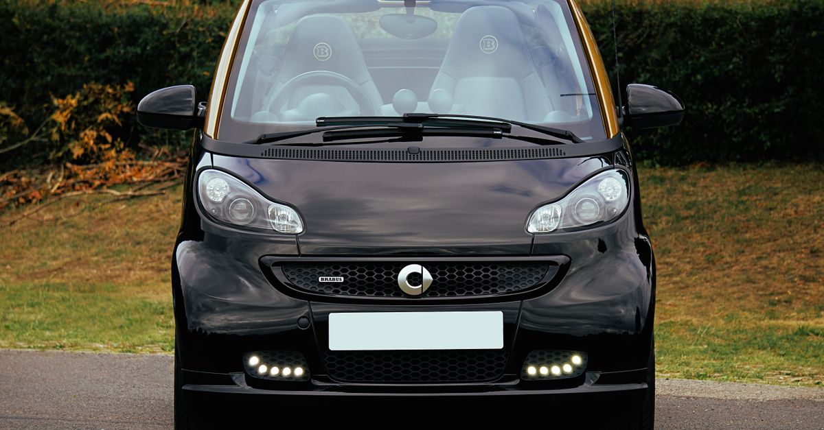 Front view of a black Brabus Smart cabriolet parked outdoors in a scenic setting.