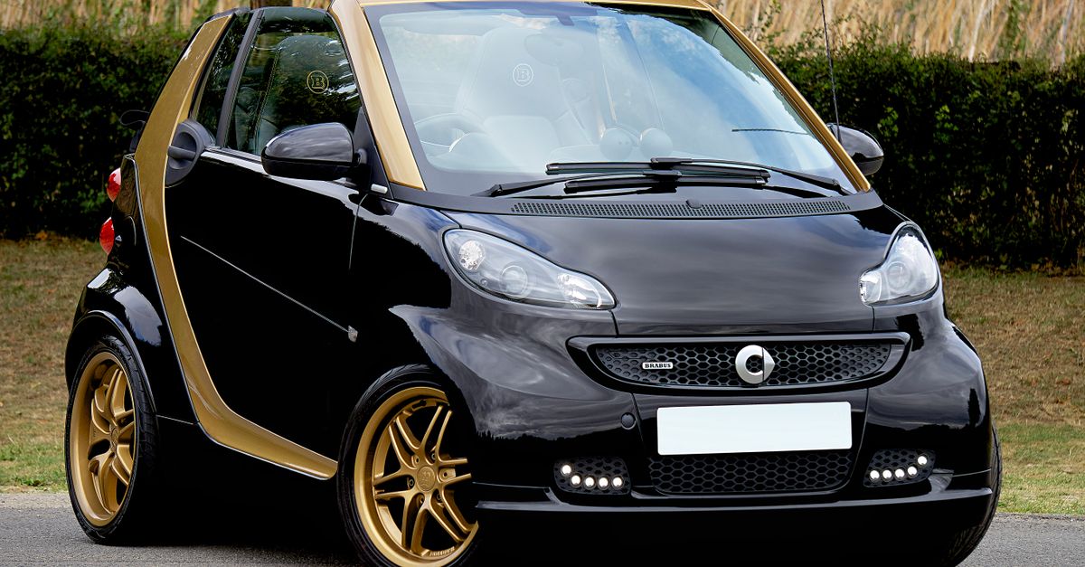 A stylish black Smart convertible with gold rims parked outside, showcasing elegance and modern design.