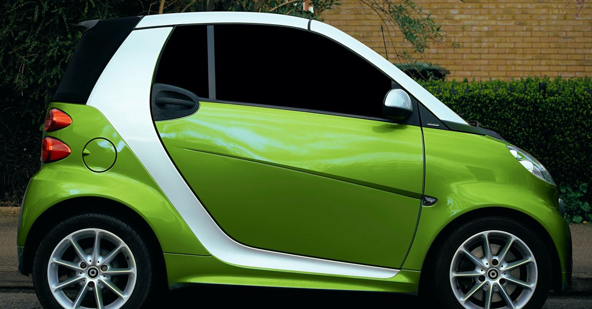 Side view of a green smart car parked on a street in Shefford, showcasing its modern design and alloy rims.