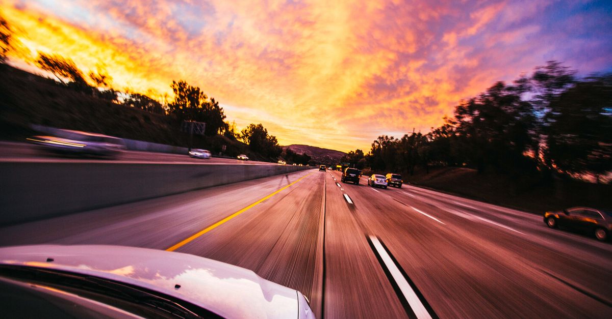 Motion blur of cars speeding on an Irvine highway at sunset with vibrant skies.