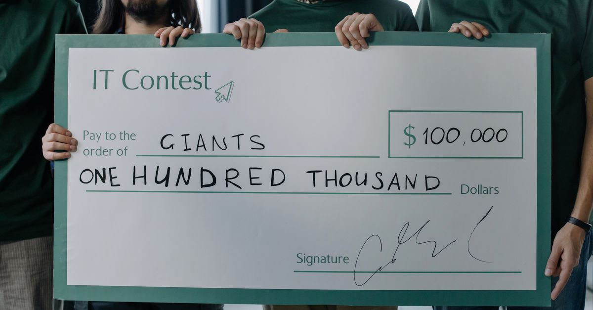 Group of men holding a $100,000 prize check after winning an IT contest.