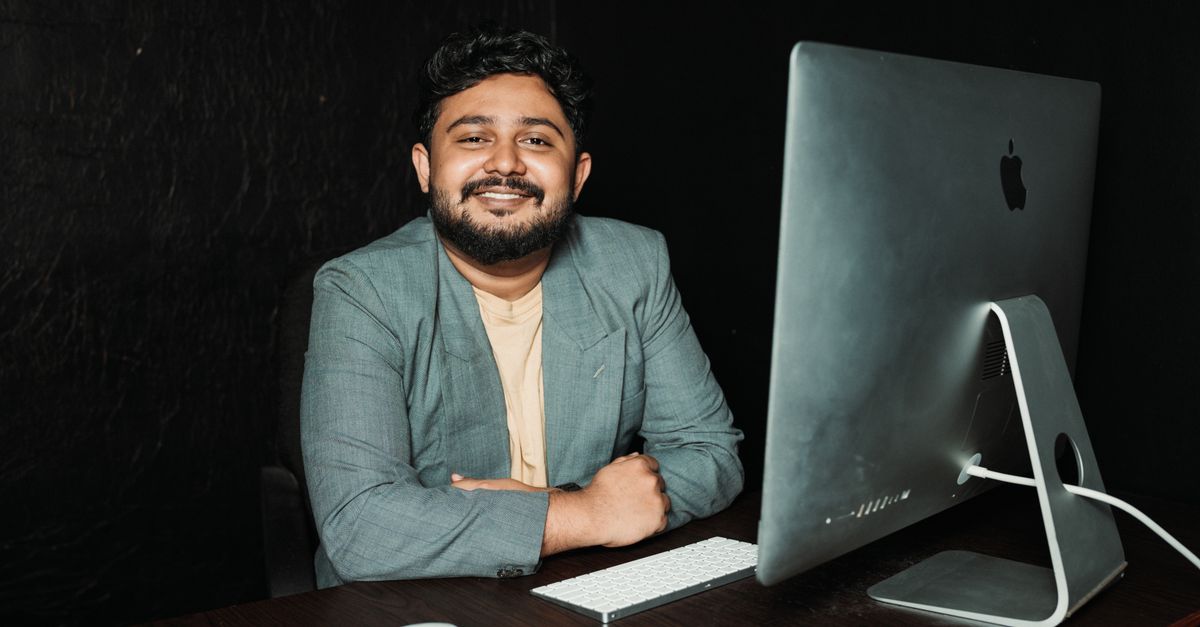 Confident businessman sitting at desk, working on computer in modern office.