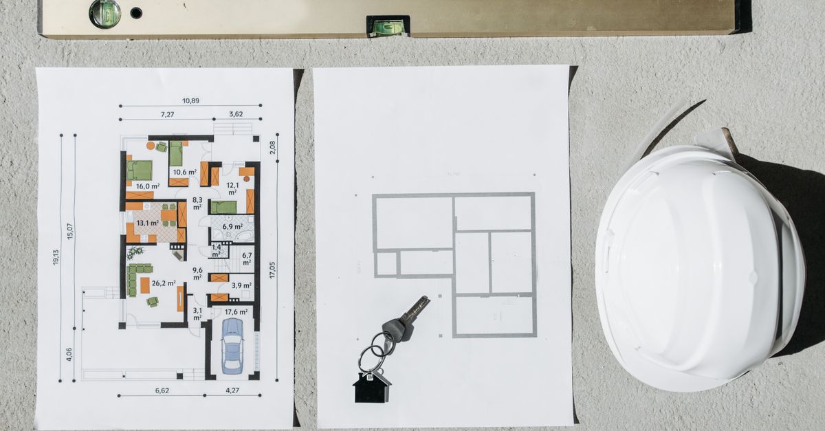 Blueprints, spirit level, and hard hat symbolize house planning.