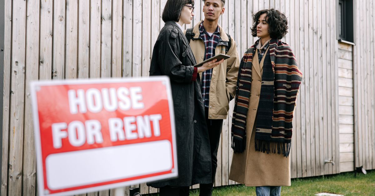 An interracial couple meets with a real estate agent to inquire about a house for rent.