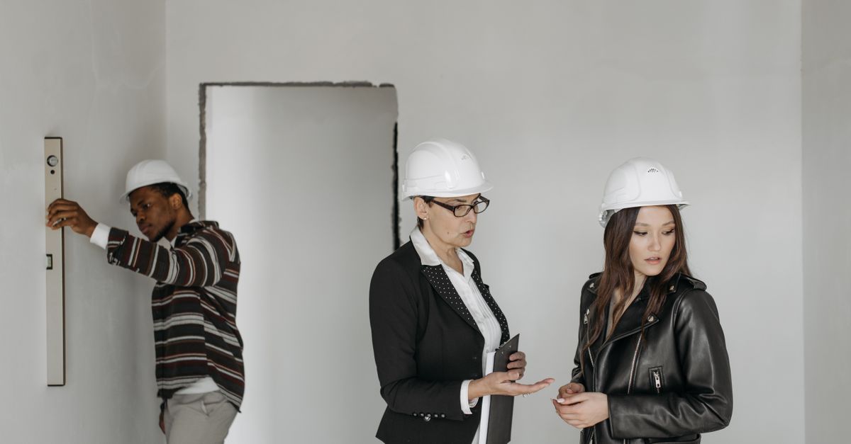 Group of architects and client inspecting a construction site wearing hard hats.