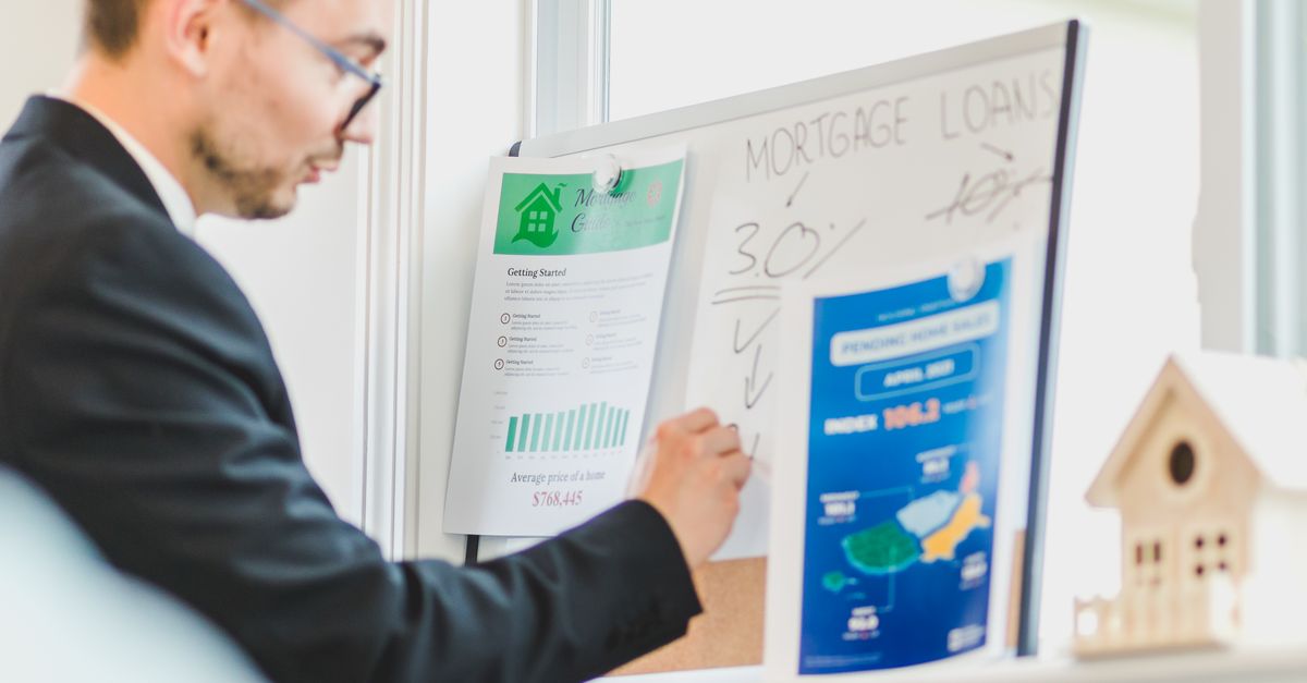 Real estate agent analyzing mortgage loan details on a whiteboard in an office setting.