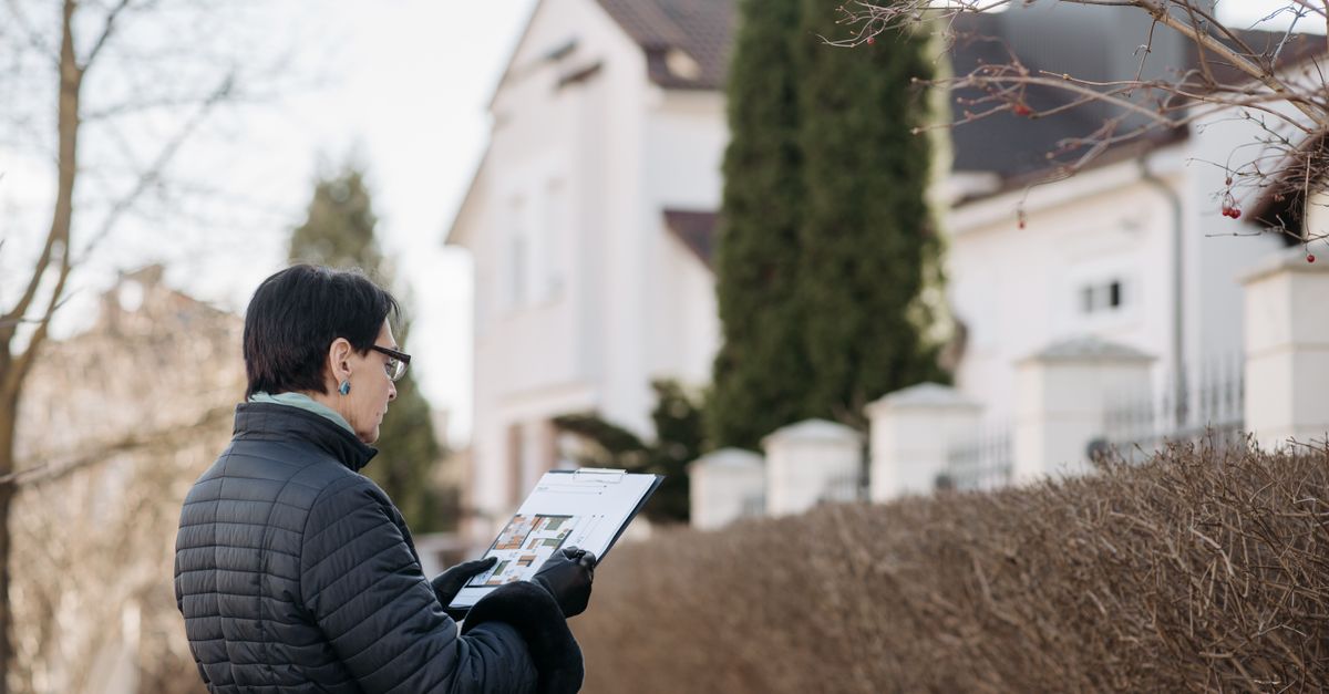 Realtor assessing house with clipboard during winter season outdoors. Ideal image for real estate content.