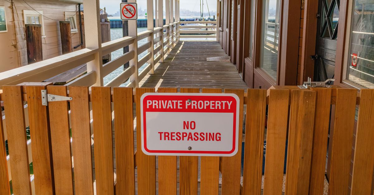 Wooden gate with a private property no trespassing sign in an outdoor setting.