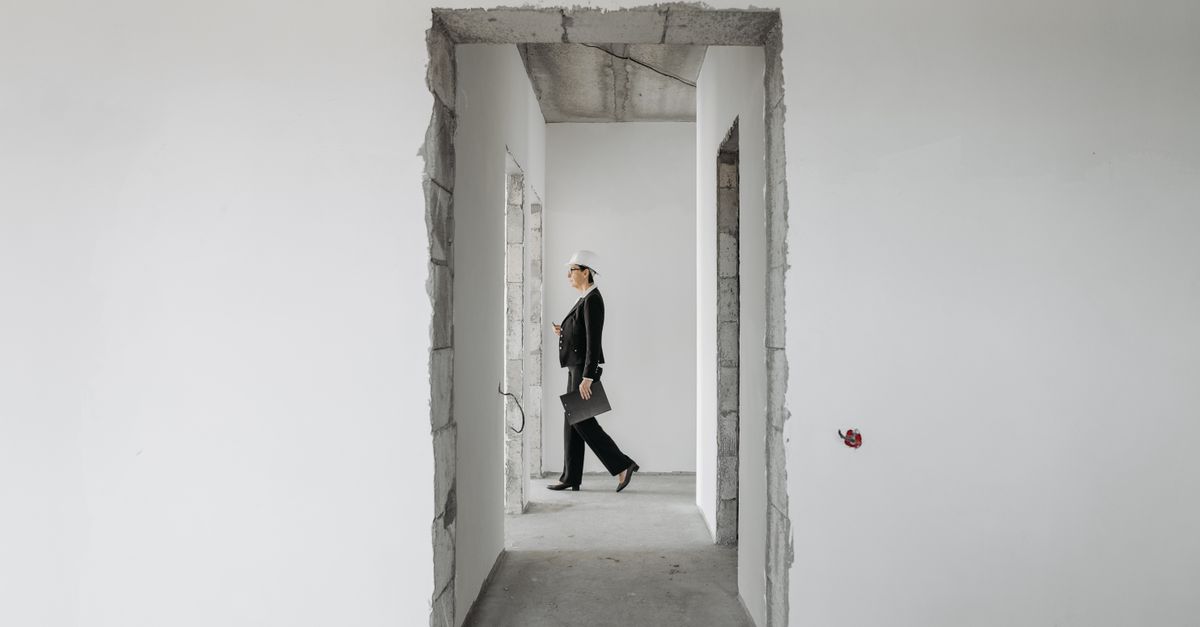 Professional woman in formal attire inspects an unfinished construction site. Ideal for real estate and construction themes.