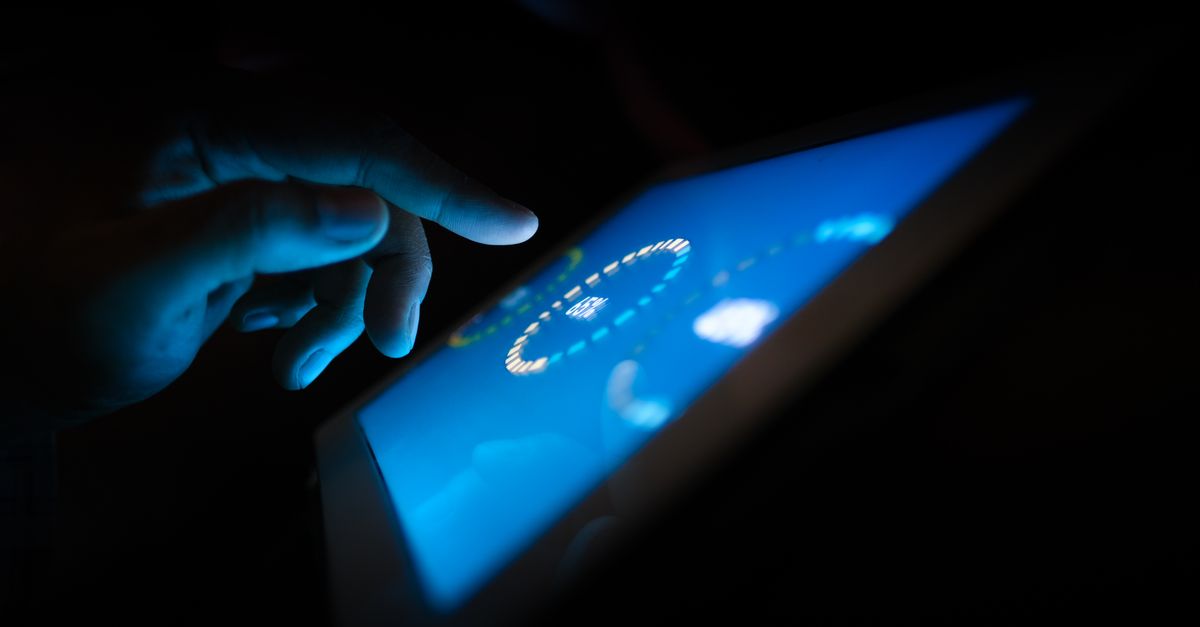 Close-up of a hand interacting with a glowing touchscreen in a dark setting, highlighting technology use.