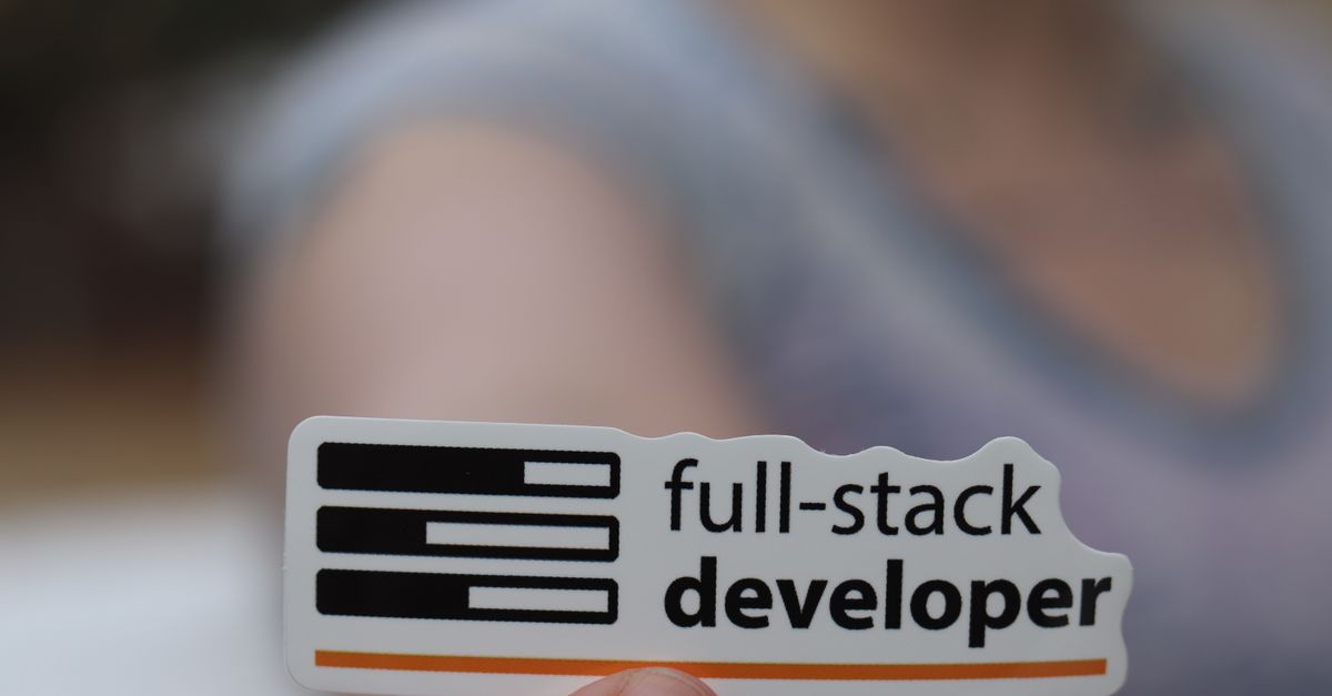 A hand holding a sticker labeled 'full-stack developer', symbolizing technology and programming skills.