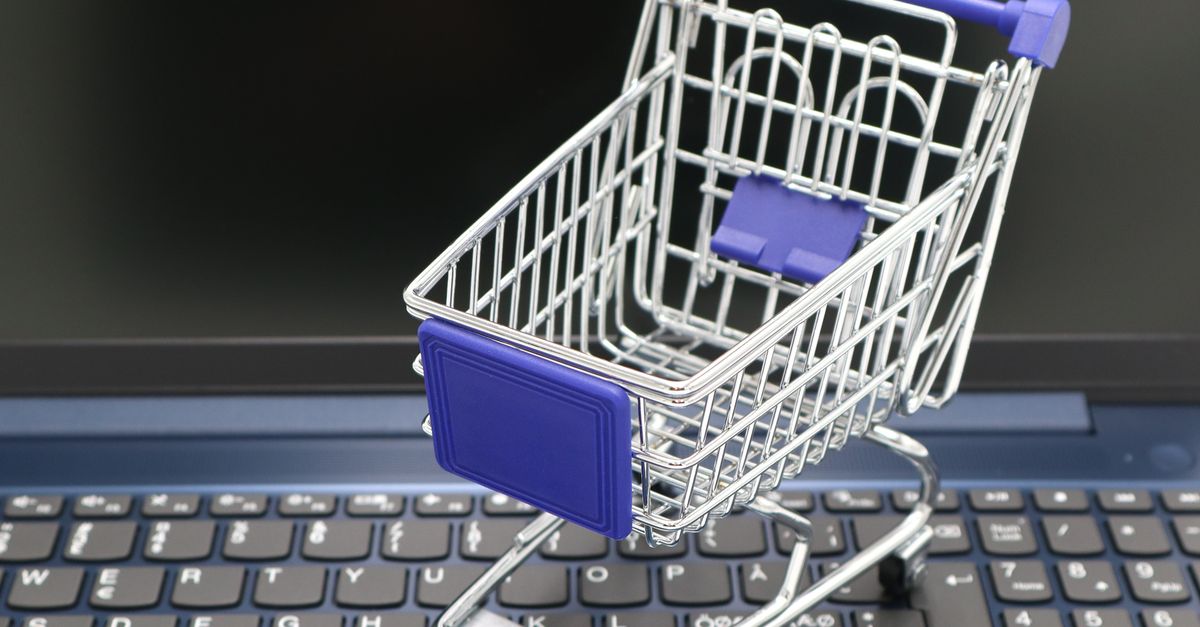 A mini shopping cart placed on a laptop keyboard, symbolizing online shopping and digital retail.