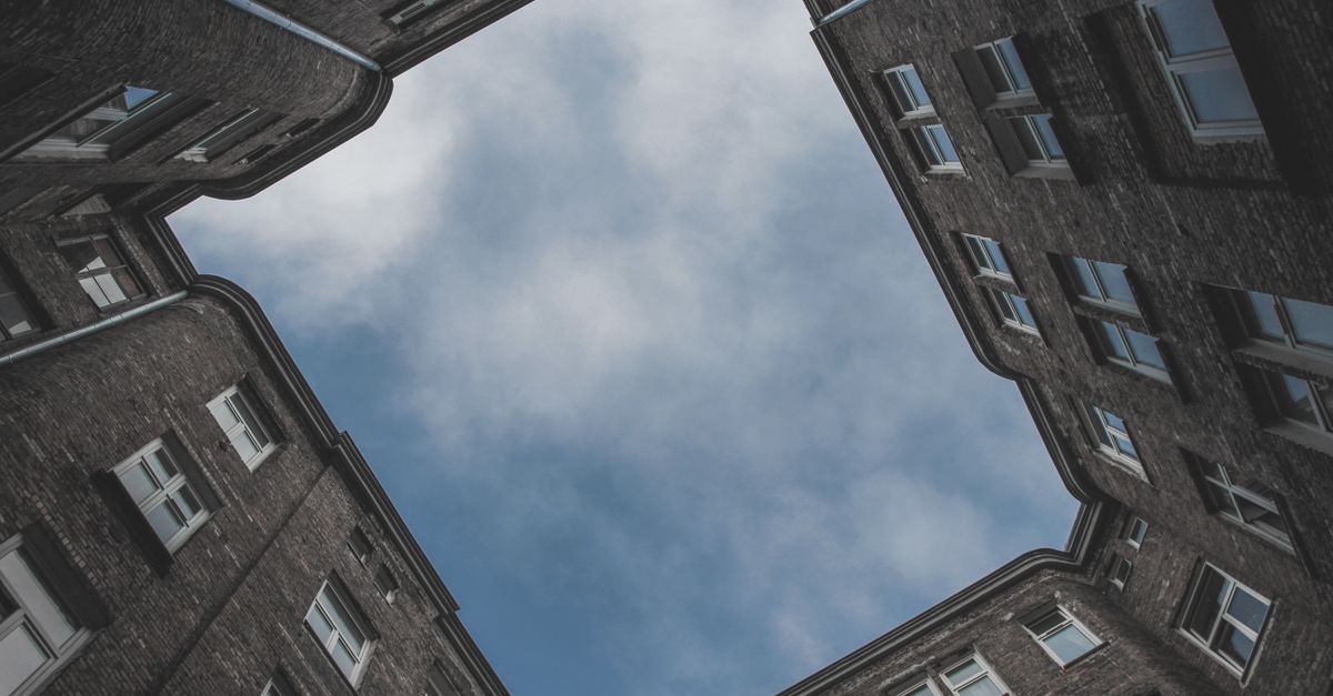 Captivating low angle view of interconnected buildings against a cloudy sky.