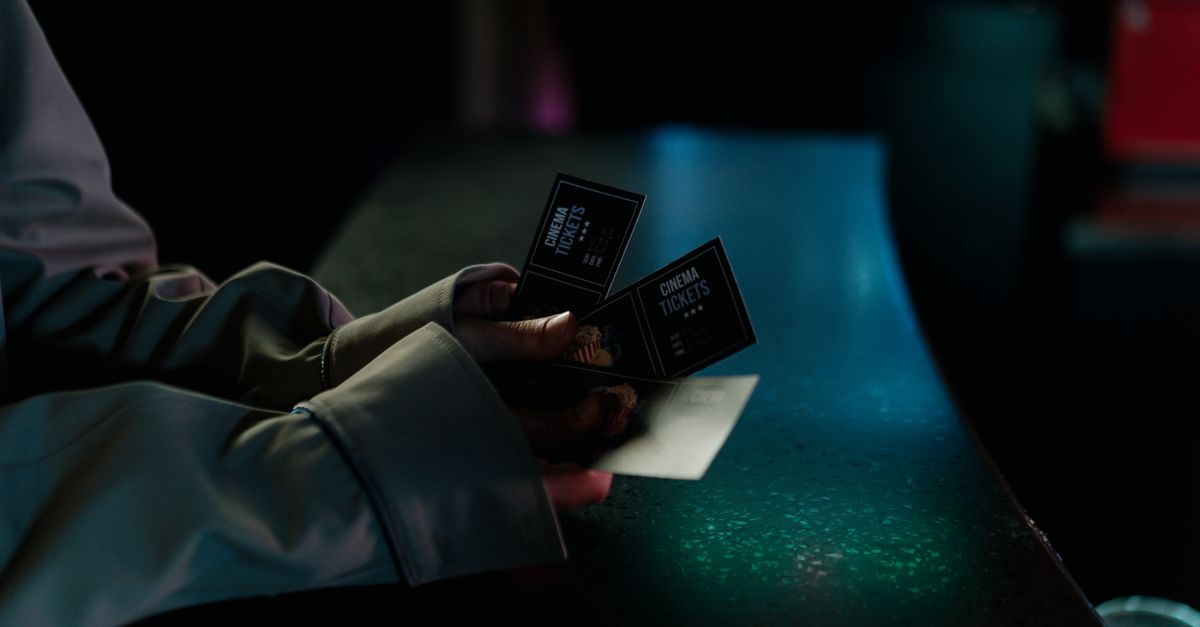 Moody image of a person holding cinema tickets at night, highlighting anticipation of a movie night.
