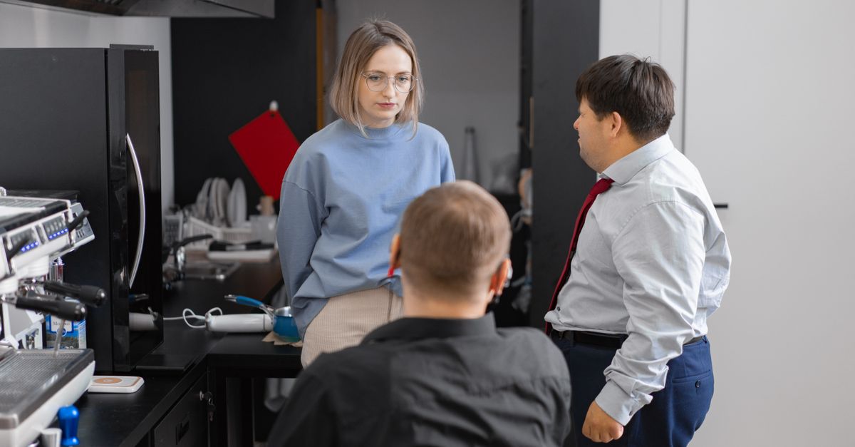 Three colleagues having a discussion in a modern office setting, promoting inclusivity and teamwork.