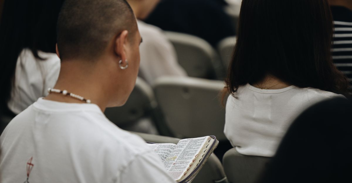 A young adult reading a Bible during a church session, reflecting faith and devotion.
