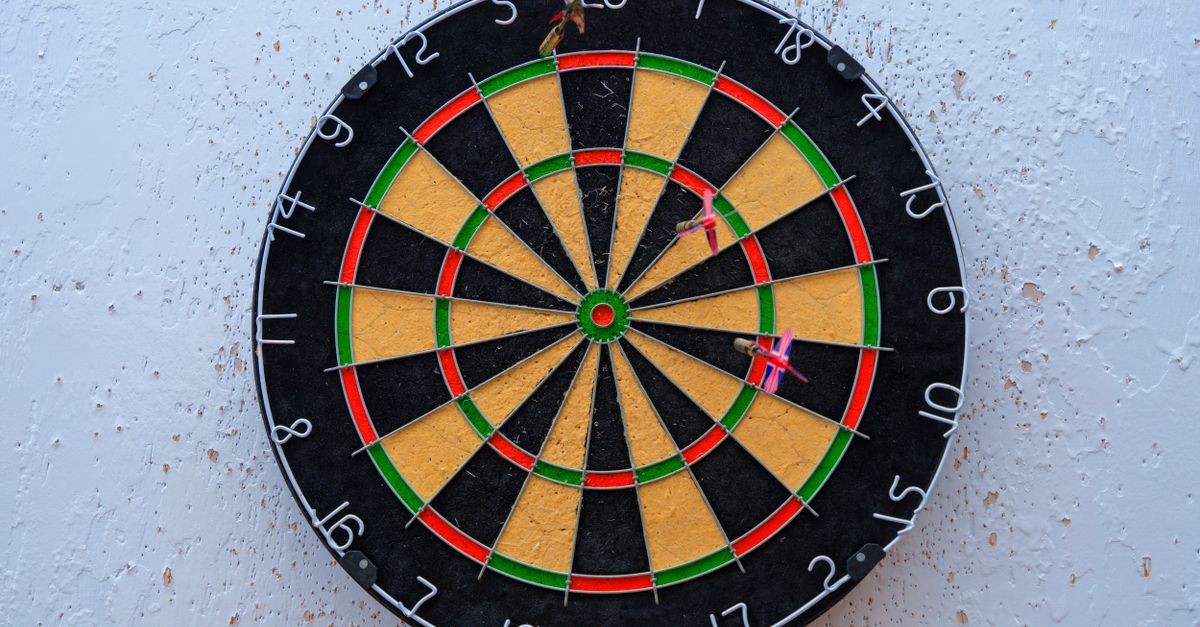 Vibrant dartboard against textured wall with darts on bullseye, symbolizing precision.