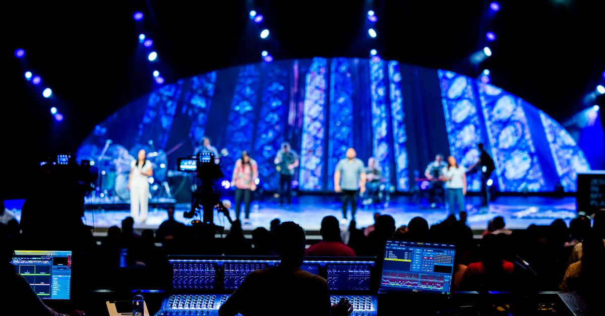 Stage performance with band, vibrant lighting, and audience at a live concert event.