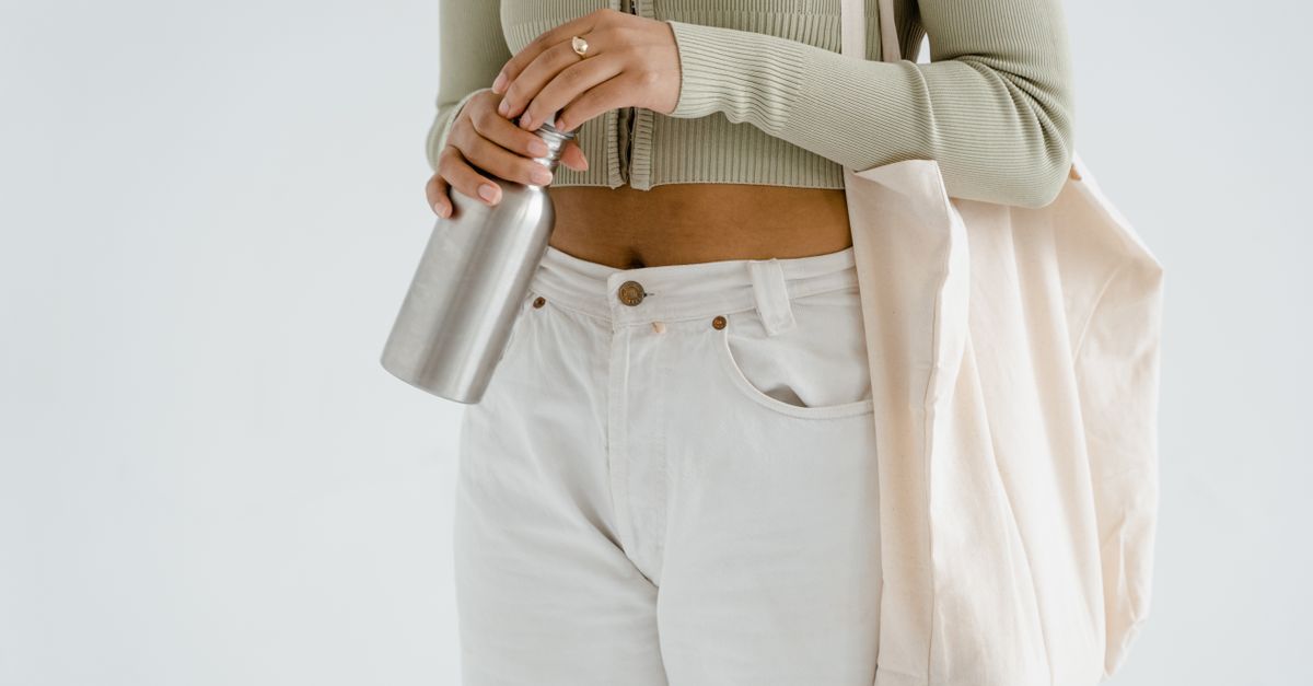 Stylish woman holding a stainless bottle and eco-friendly bag, promoting sustainable fashion.