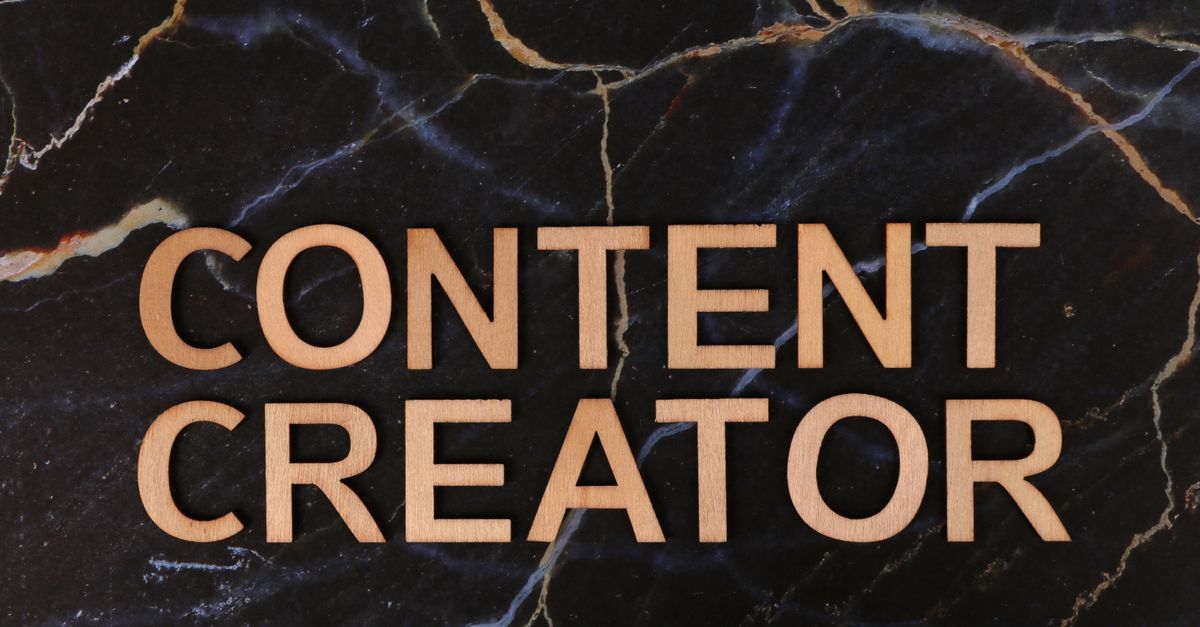 Wooden letters spelling 'CONTENT CREATOR' on a dark marble background.