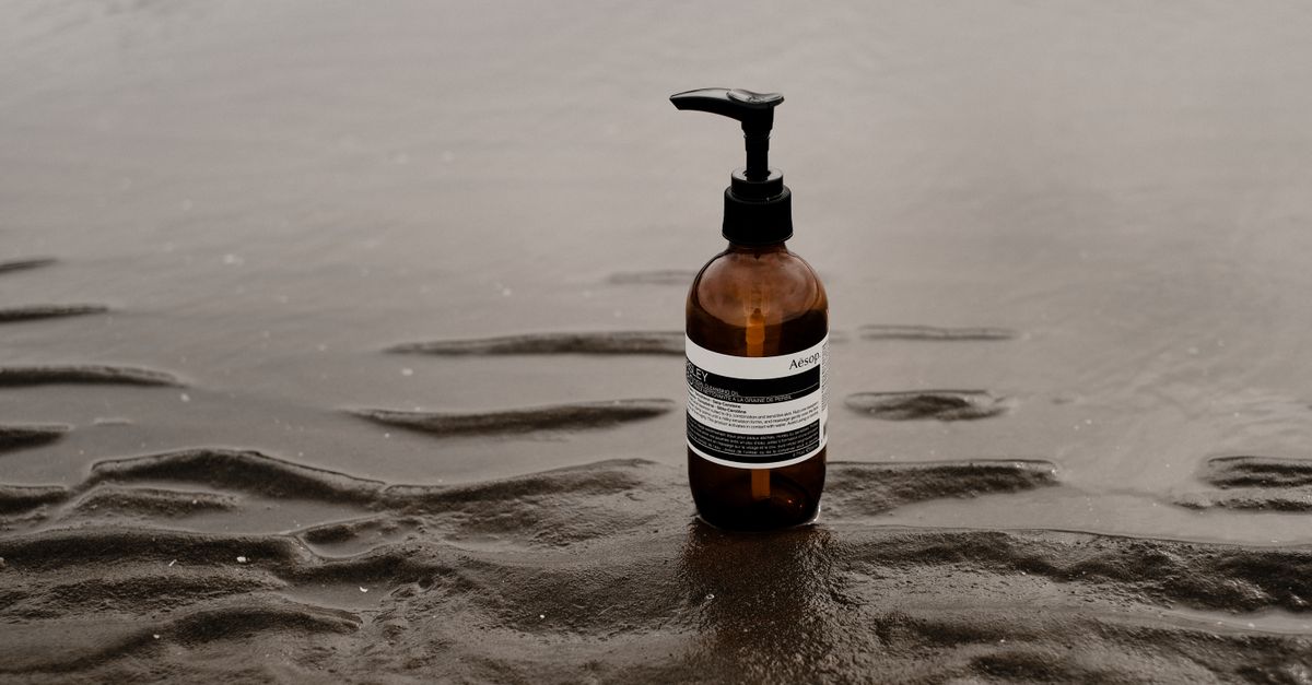 Minimalist image of a skincare bottle placed on a wet sandy beach, emphasizing tranquility.