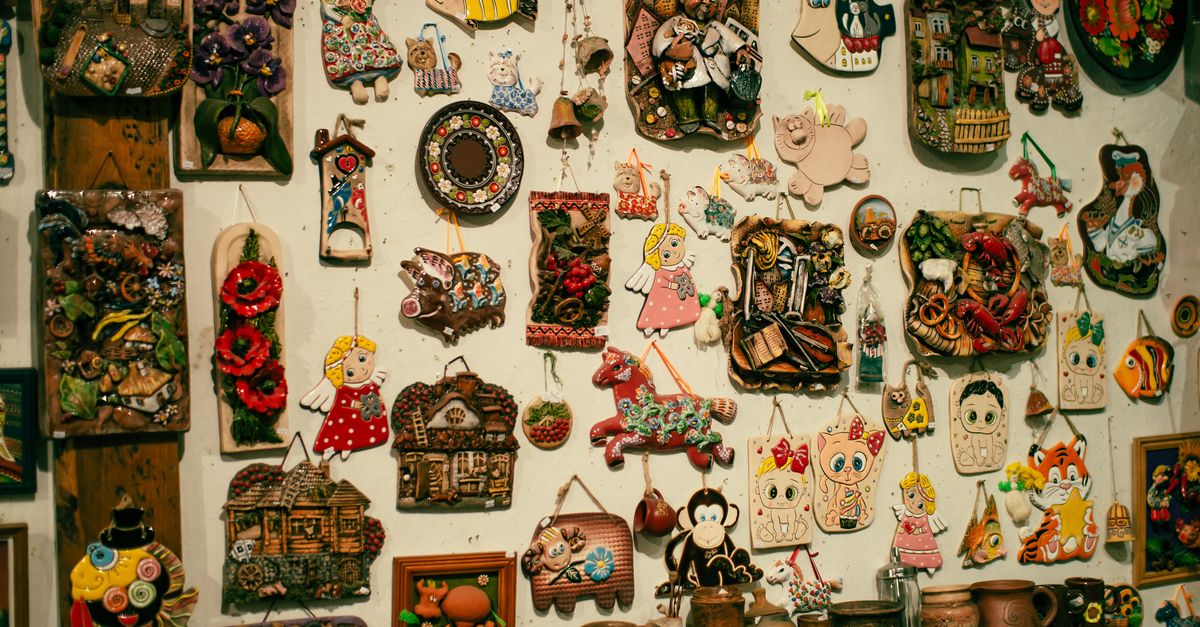 A vibrant assortment of handmade wall art including colorful pendants and clay figures.