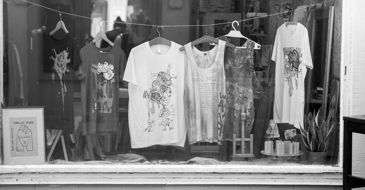 Monochrome window display featuring graphic t-shirts and merchandise in a retail store setting.