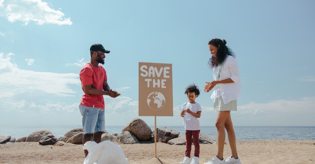 Family participates in beach cleanup with a 'Save the Planet' sign promoting environmental awareness.