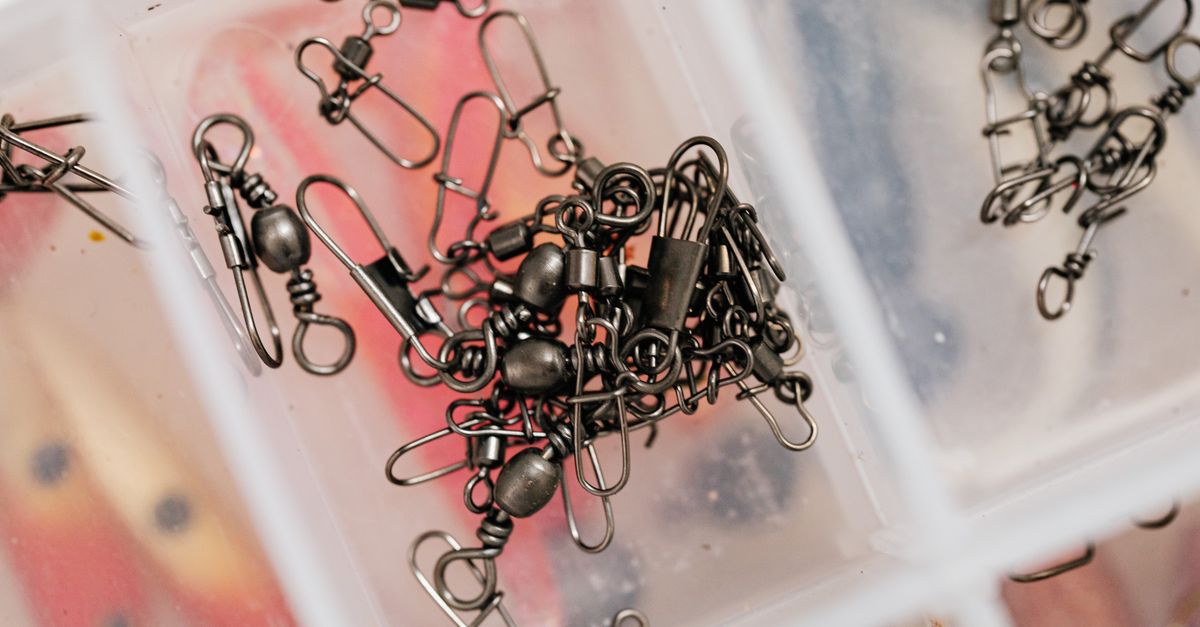 Detailed view of fishing swivels stored neatly in a clear plastic box.