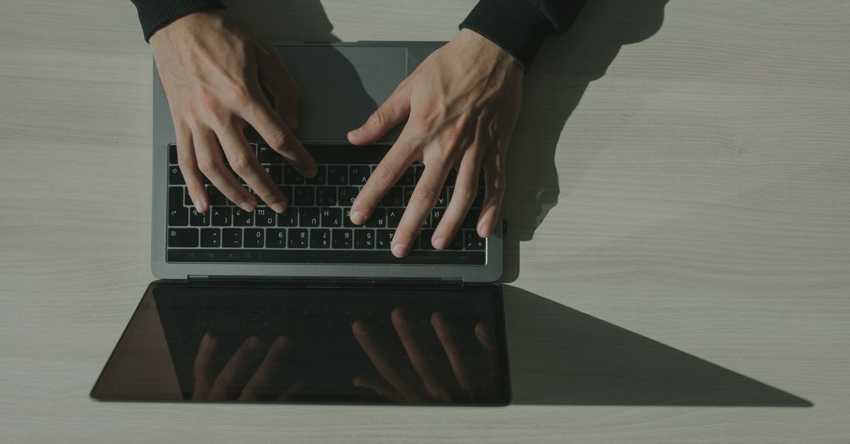 Overhead shot of hands typing on a laptop, showcasing technology and internet usage.