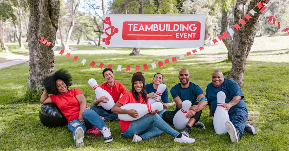 A joyful group participates in a team building event outdoors with bowling pins.