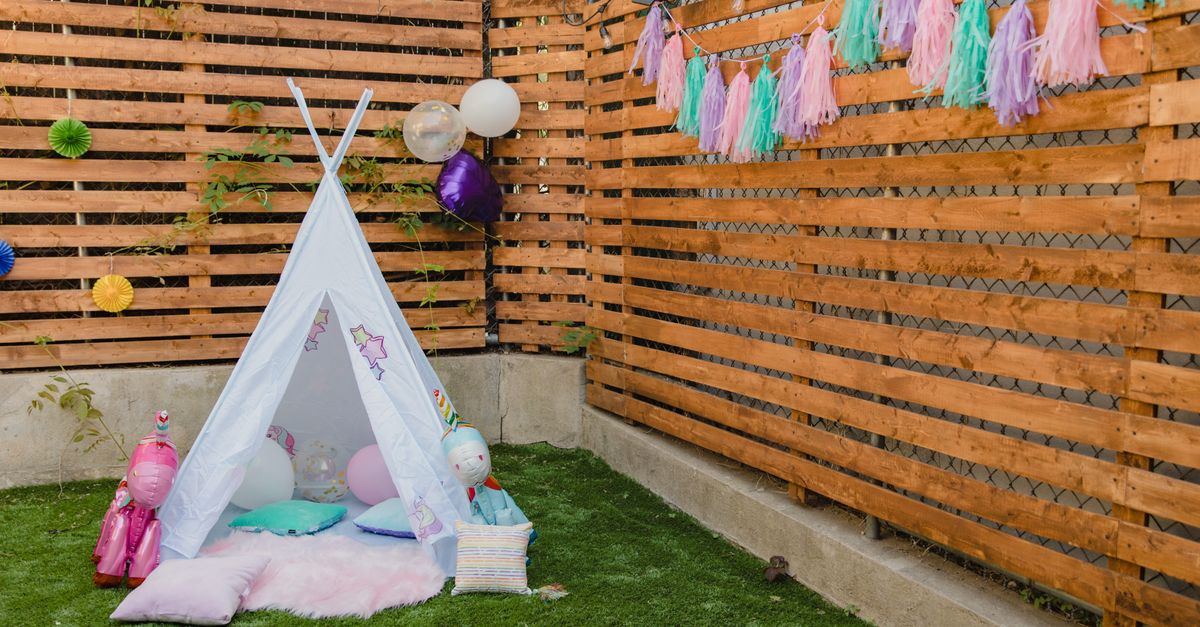 Charming children's party setup with colorful decorations and a tent in a garden setting.