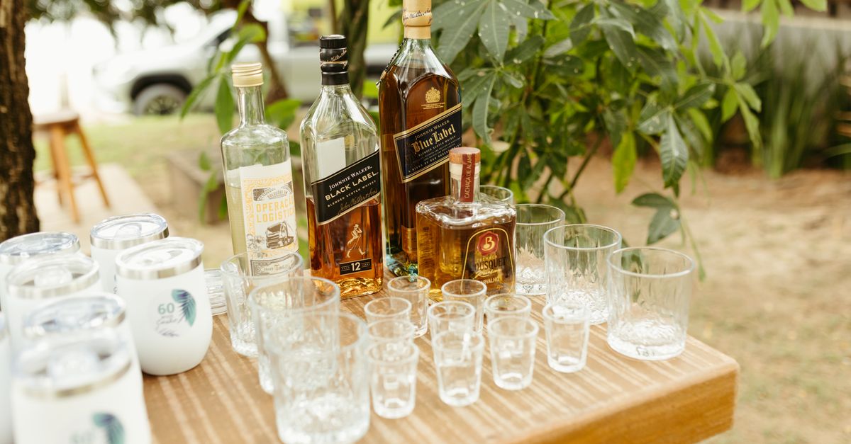 An elegant outdoor table setting with whiskey bottles and glasses for a tasting event.