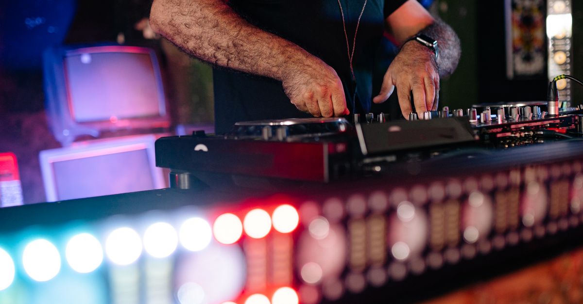 Close-up of a DJ mixing music at a lively nightclub event, creating an energetic party atmosphere.