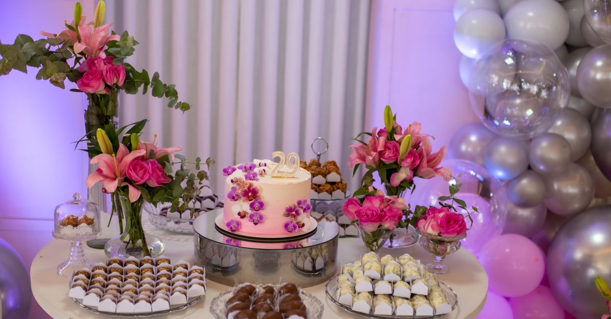 Celebrate with a beautifully decorated birthday cake surrounded by floral arrangements and sweets.