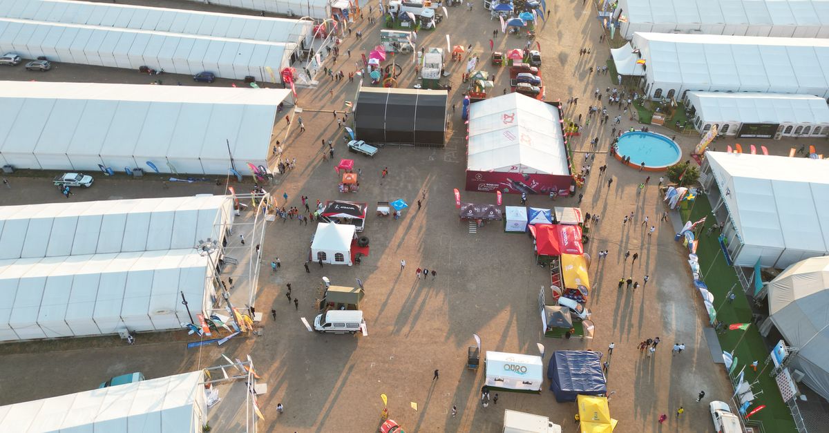 Bird's-eye view of a lively outdoor event with multiple white tents and people.