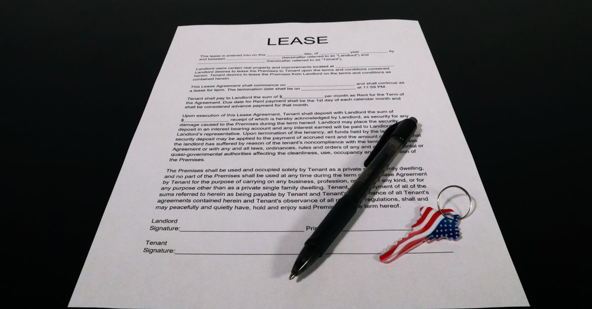 Lease agreement document with pen and American flag keychain on a black table.