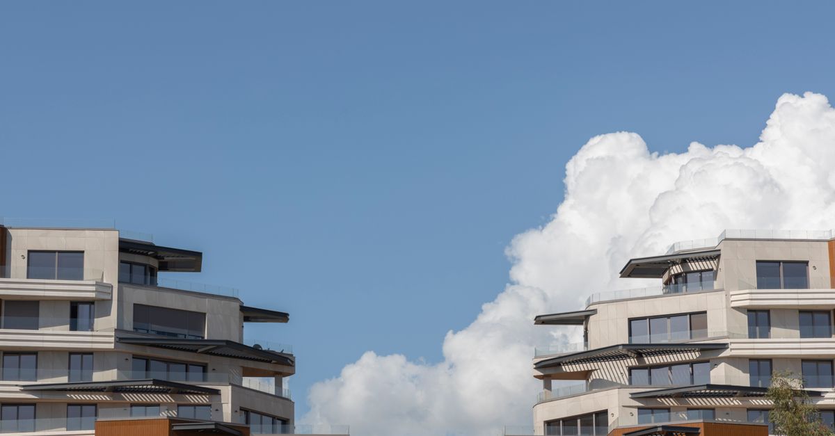 Contemporary urban architecture under a bright blue sky with clouds.
