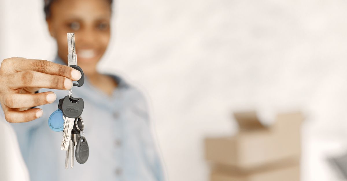 Close-up of a woman holding keys with a blurred background, symbolizing a new home or real estate concept.