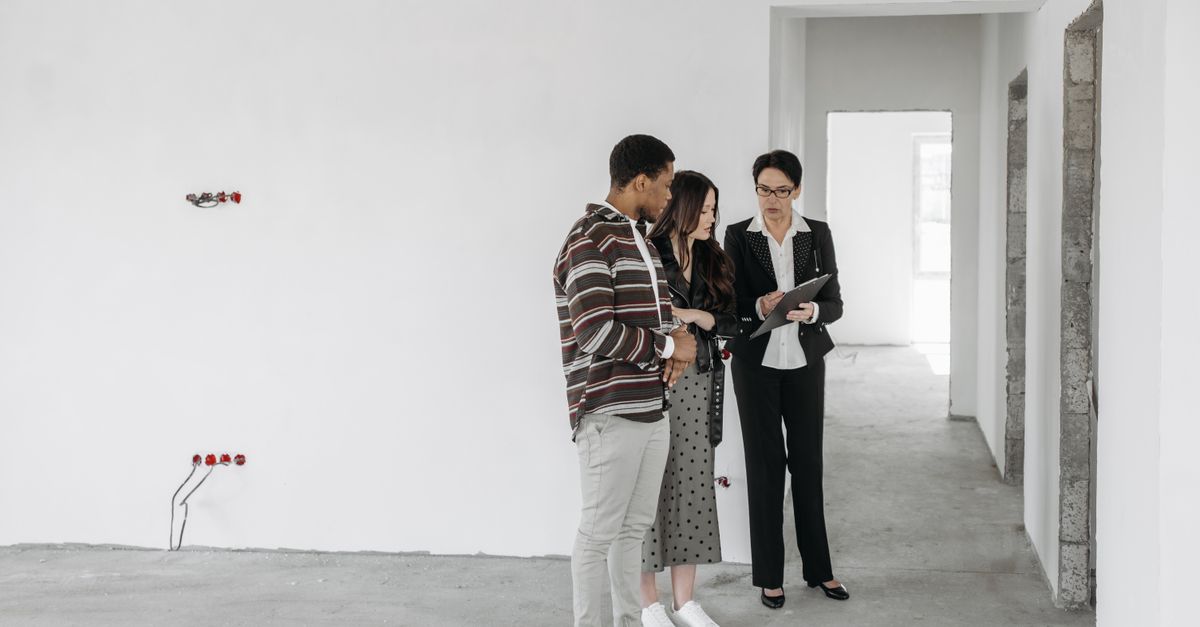 A couple and realtor discuss details in an unfinished property. Ideal for real estate themes.