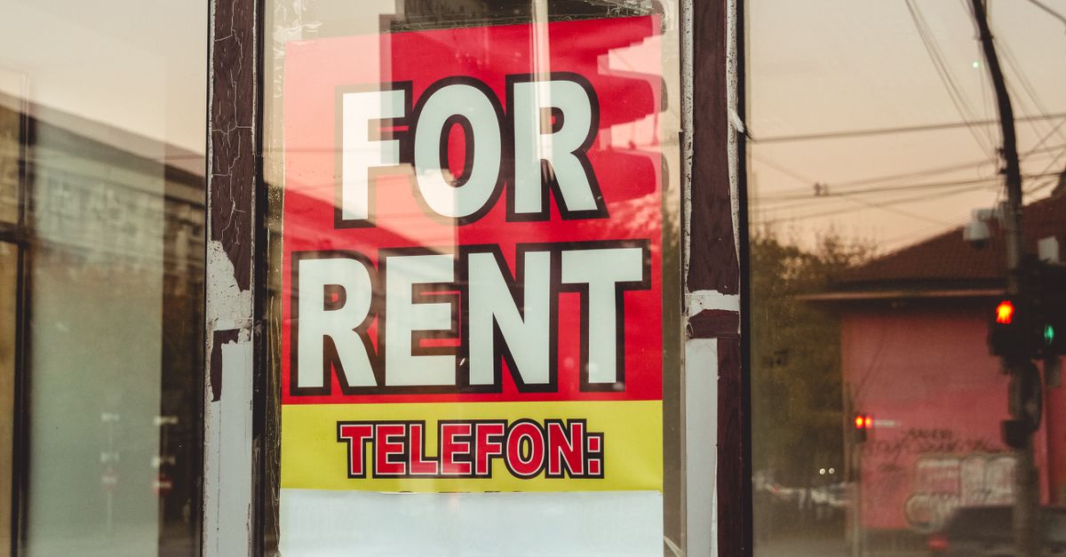 Reflection of a cityscape on a window with a 'For Rent' sign and sunset glow.