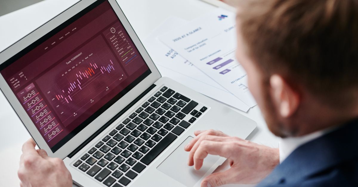 Businessman reviewing data analytics dashboard on laptop in bright office.