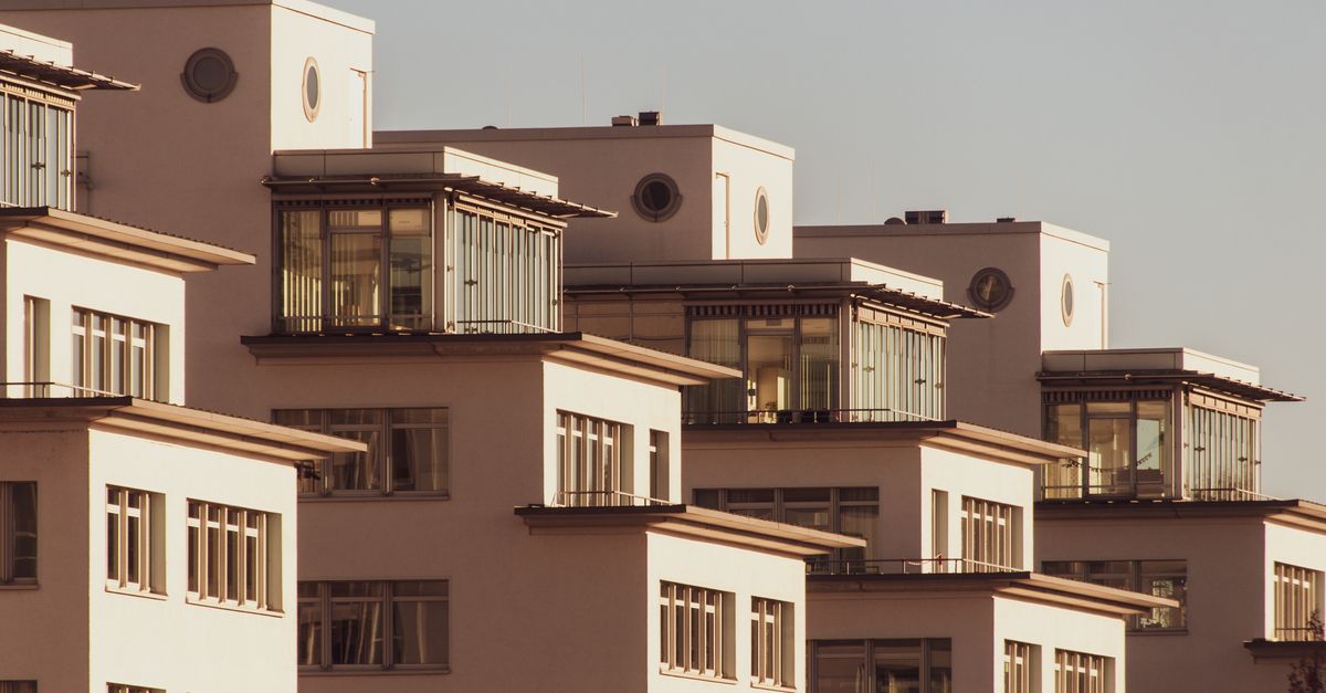 Explore modern white apartment blocks with stylish glass features, bathed in soft daylight.